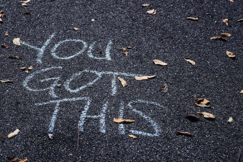 Frase "you got this" - você consegue isso - escrita no asfalto com folhas no entorno.