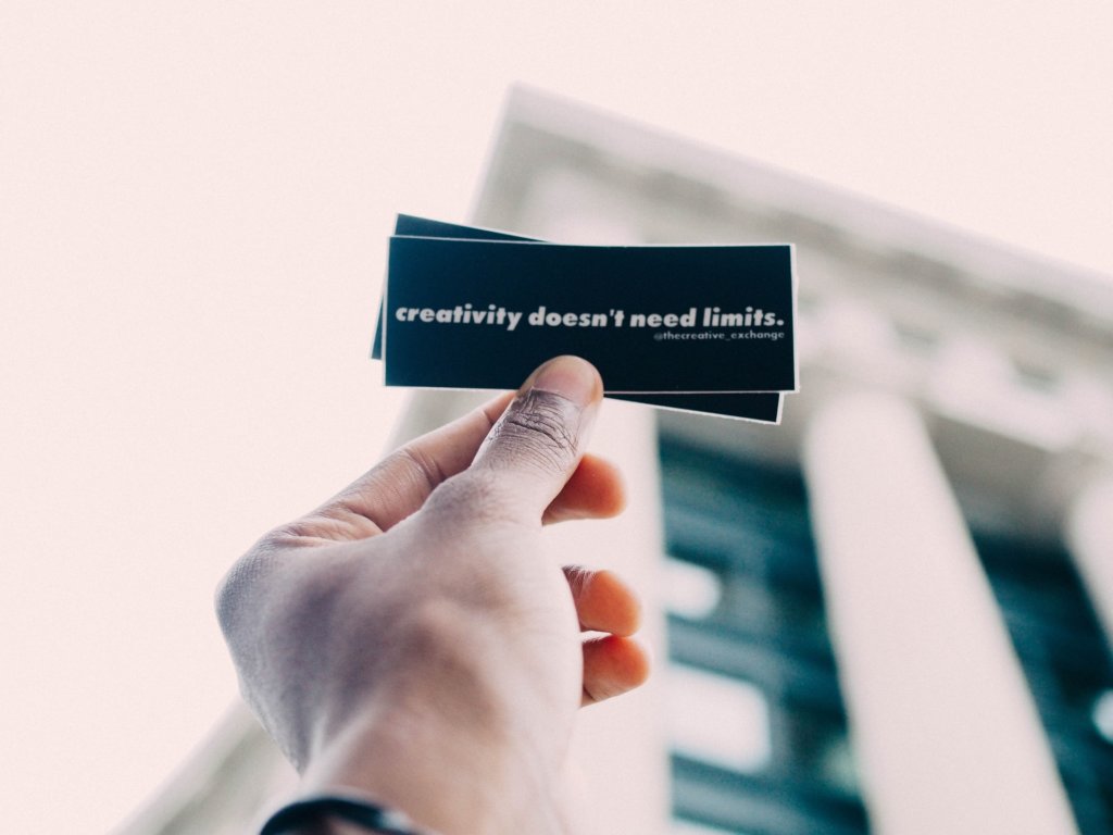 Mão segurando papel escrito: "creativity doesn't need limits." Tradução: Criatividade não precisa de limites